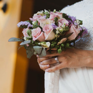 bride wearing 1 carat diamond ring holding bouquet
