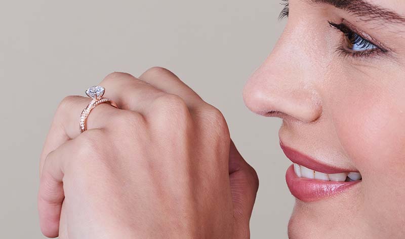 Woman wearing 14K rose gold lab grown diamond engagement ring on hand side view