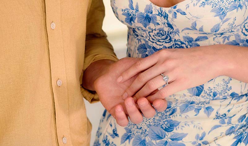 Couple holding hand with woman wearing cushion cut lab grown diamond engagement ring