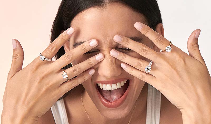 Woman wearing two princess cut lab grown diamond engagement rings on each hand