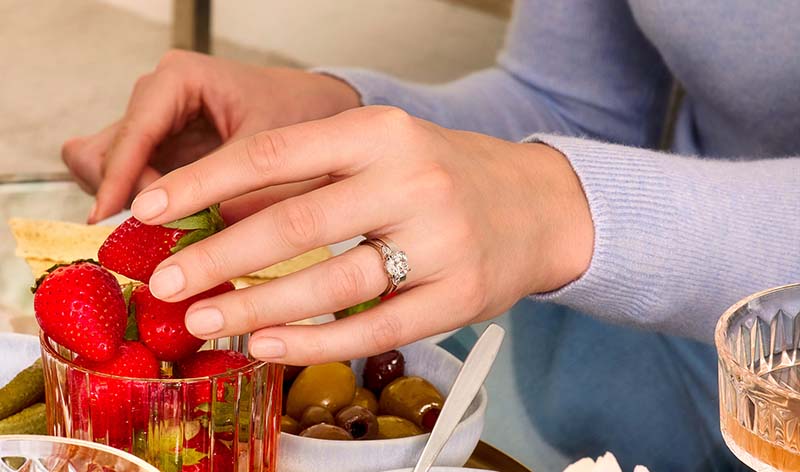 Woman wearing three stone lab diamond engagement ring on hand