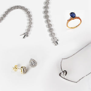 Wedding day jewelry: diamond bracelet, pear lab diamond halo stud earrings, blue sapphire ring, and heart necklace