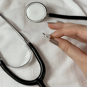 Female holding Lily diamond engagement ring with stethoscope