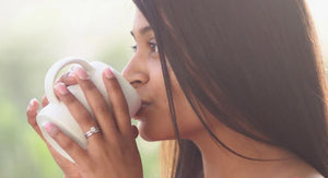 woman sipping coffee wearing one carat diamond ring