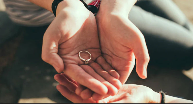 man holding engagement ring in cupped hands