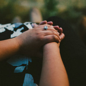 couple holding hands with blue diamond engagement ring