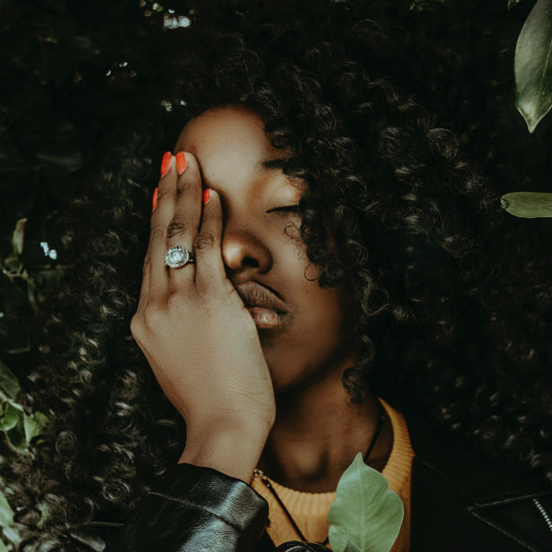woman wearing colored diamond ring touching face