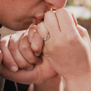 man kissing woman's hand wearing a diamond ring