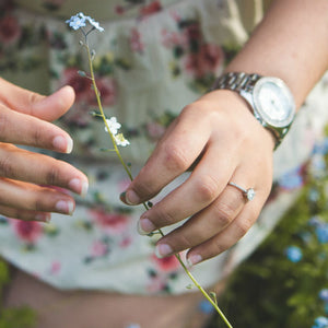 woman holding flower wearing diamond engagement ring