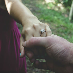 woman holding man's hand and wearing engagement ring