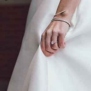 woman wearing oval engagement ring holding dress