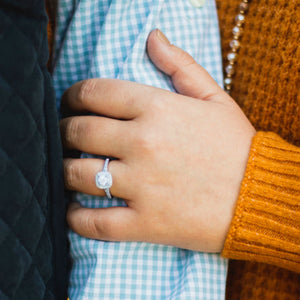 woman wearing square halo engagement ring holding man's arm