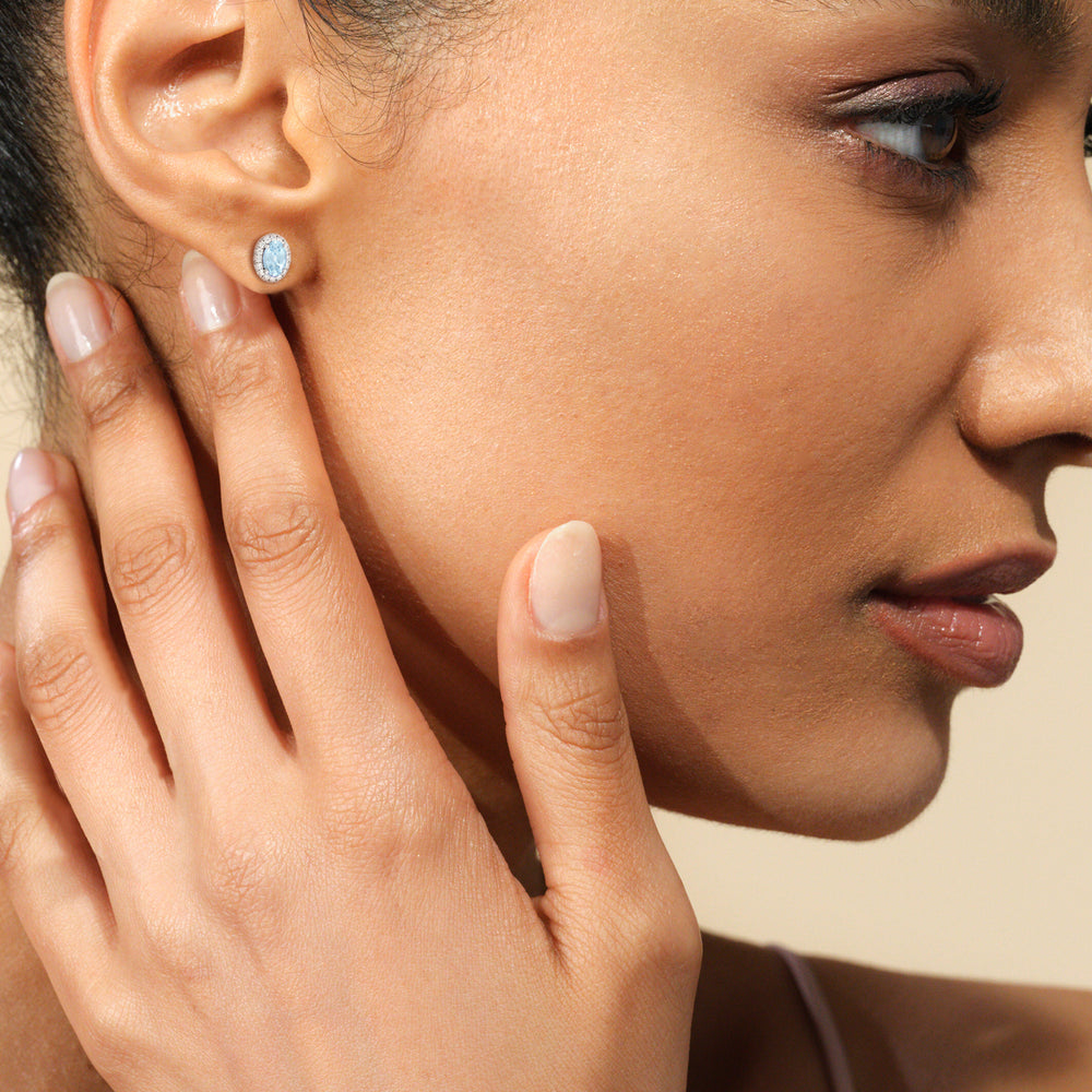 Model Wearing Oval Aquamarine and Lab Diamond Classic Solitaire Halo Earrings view