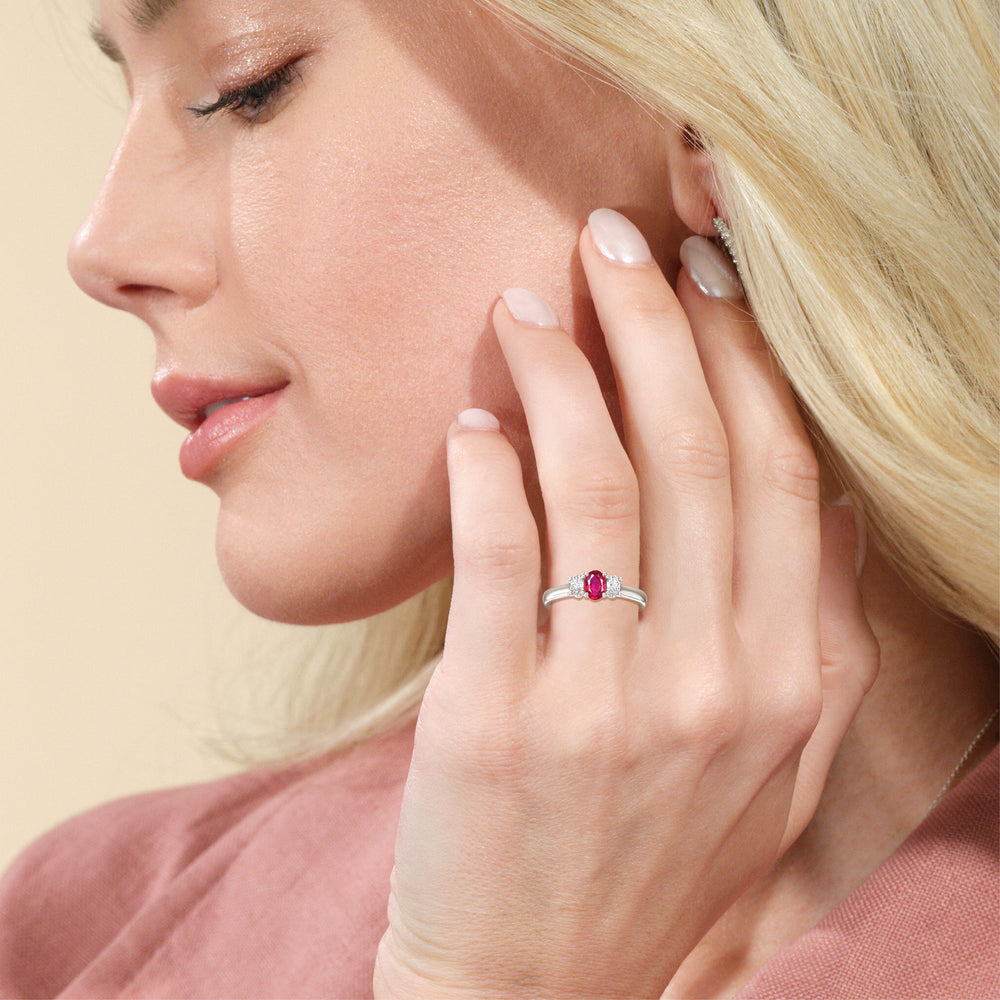 Model Wearing Created Ruby Center And Oval Cut Three Stone Diamond Ring view