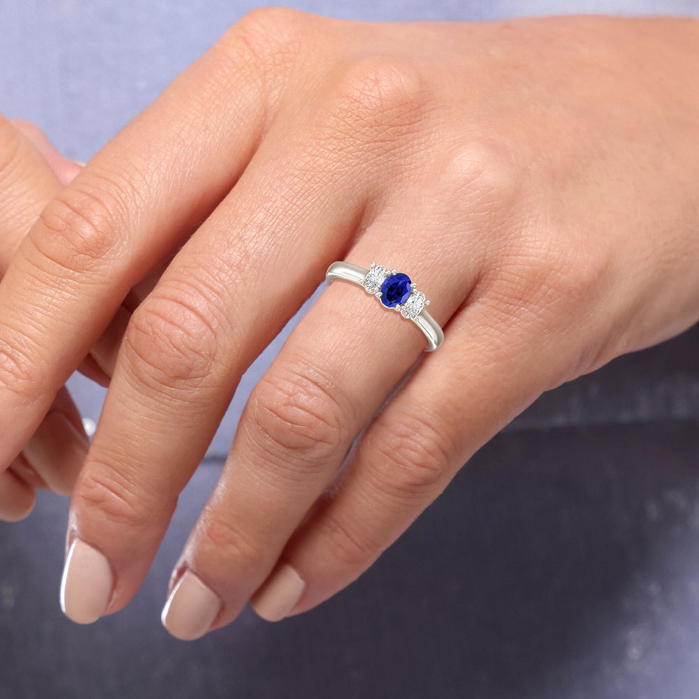 Model Wearing Created Sapphire Center And Oval Cut Three Stone Diamond Ring view