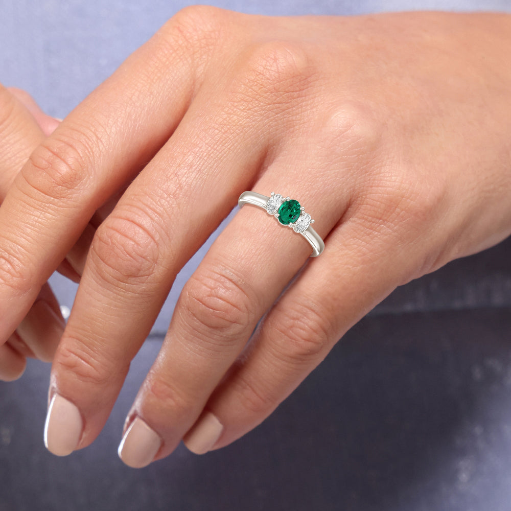 Model Wearing Created Emerald Center And Oval Cut Three Stone Diamond Ring view